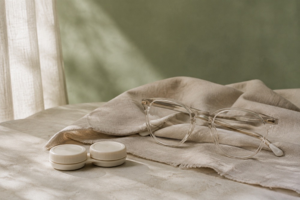 Estuche de lentes de contacto cerrado junto a unas gafas
